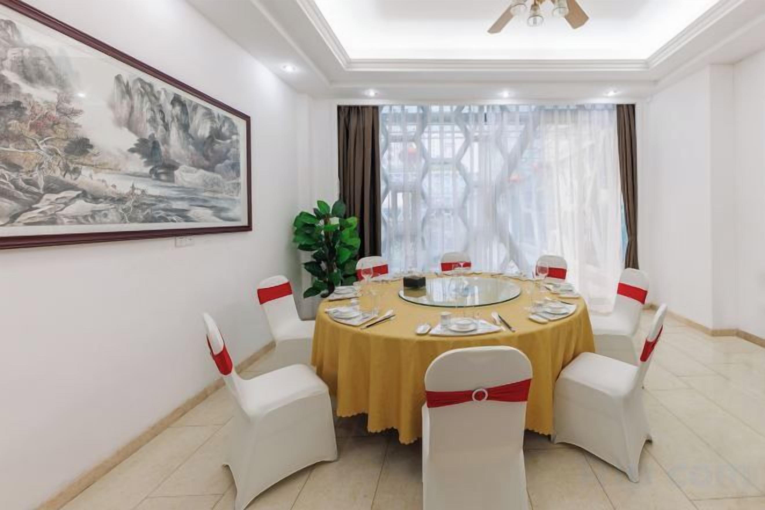 Uma sala de jantar com uma mesa redonda, cadeiras brancas e um quadro na parede.