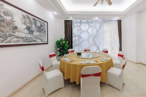 A dining room with a round table, white chairs, and a painting on the wall. - Sunflower Hotel & Residence Serviced apartment (Shenzhen)