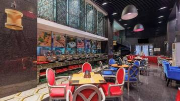 Interior de restaurante com balcão extenso, várias mesas e cadeiras.