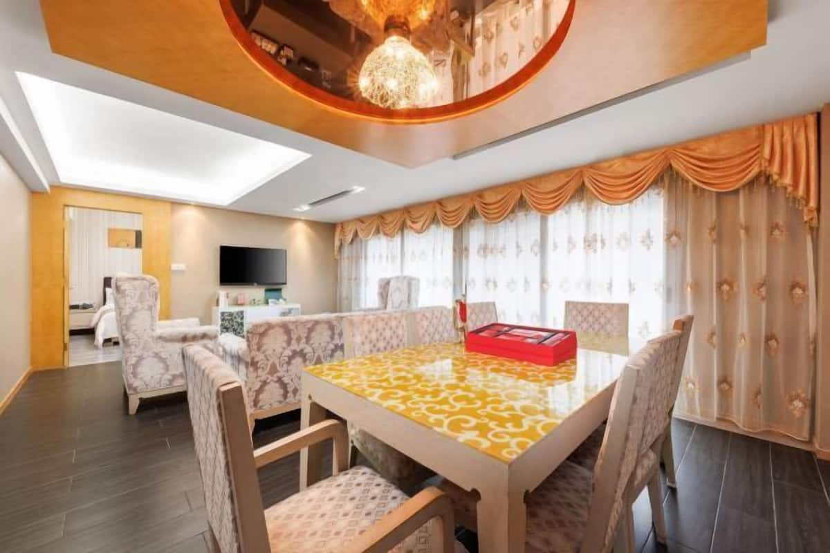 A dining area with a patterned table, chairs, and a television in the background.
