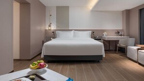 A modern hotel room with a large bed, a desk, a chair, and a small kitchenette. - Sunflower Hotel & Residence Serviced apartment (Shenzhen)