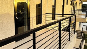 Un edificio con fachada texturizada, una puerta de marco negro y un equipo de aire acondicionado montado en la pared exterior.