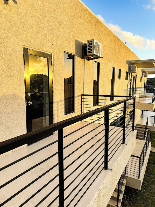 A building with a textured facade, a black-framed door, and an air conditioning unit mounted on the exterior wall.