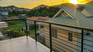 Un balcón con barandilla metálica que da a zona residencial con casas y una montaña al fondo.