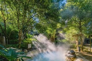 Un cadre naturel agrémenté d’une structure en pierre, d’arbres et d’une atmosphère brumeuse.