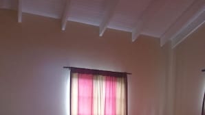 A bedroom with a bed, a nightstand, and a window with curtains. - Room-near air and Ferry Ports, Shops & b (Castries)