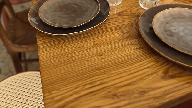 A wooden dining table set with plates, glasses, and a candle. - Cayeux sur Mer. Family home 2 steps from the sea! (Cayeux-sur-Mer)