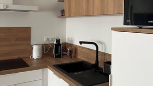 A modern kitchen with a wooden countertop, a black sink, a coffee maker, a kettle, and a Samsung TV on a wooden shelf. - Cayeux sur Mer. Family home 2 steps from the sea! (Cayeux-sur-Mer)