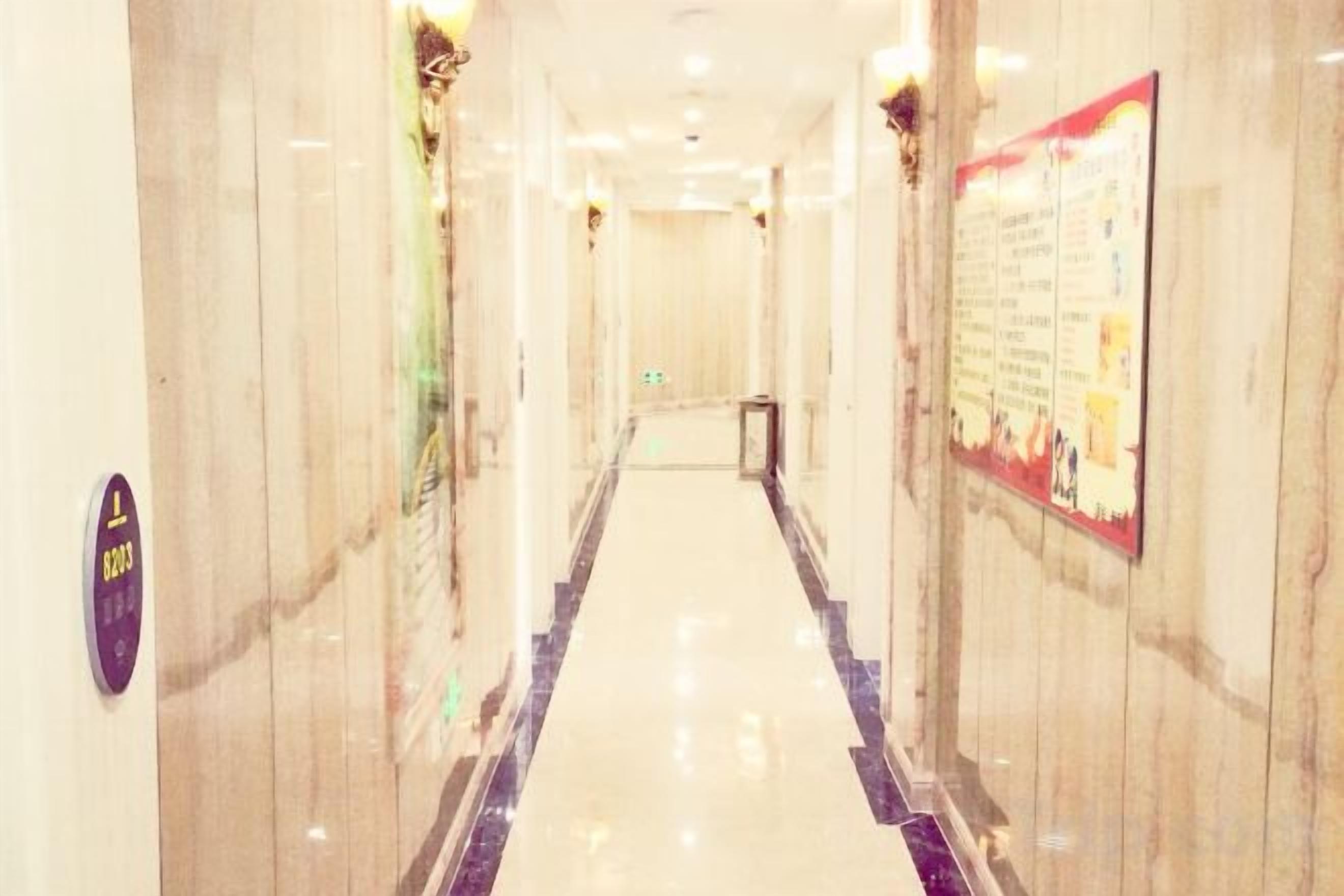 A hotel corridor with marble walls, a polished floor, and a poster on the right wall.