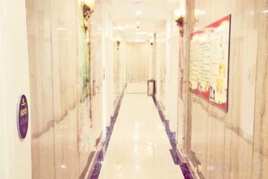 A hotel corridor with marble walls, a polished floor, and a poster on the right wall. - Pebble Motel (Shanghai Gucun Park Jutai Road) (Shanghai)