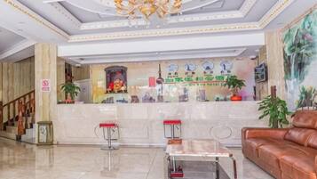A lobby with a reception desk, a chandelier, a sofa, and a coffee table.