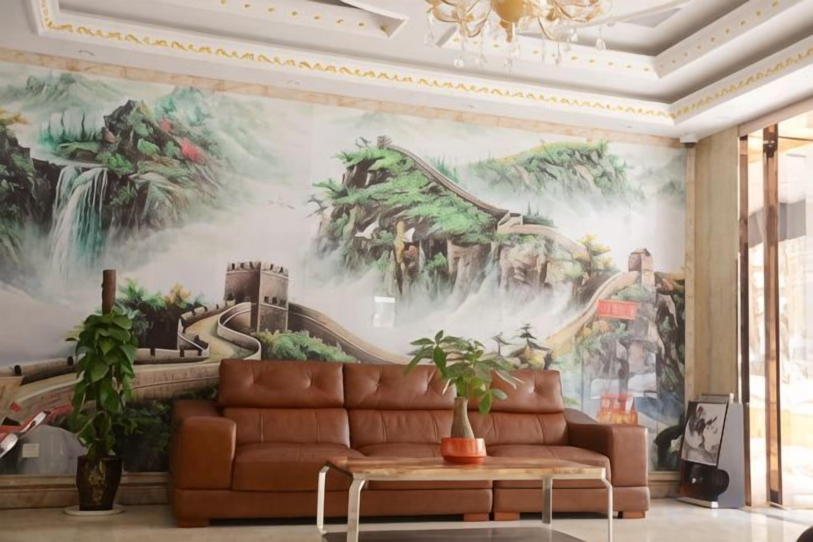 A lobby with a mural of a mountainous landscape, a brown leather sofa, and a coffee table with a potted plant.