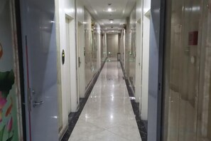 A long, narrow hotel corridor with doors on both sides, leading to rooms.