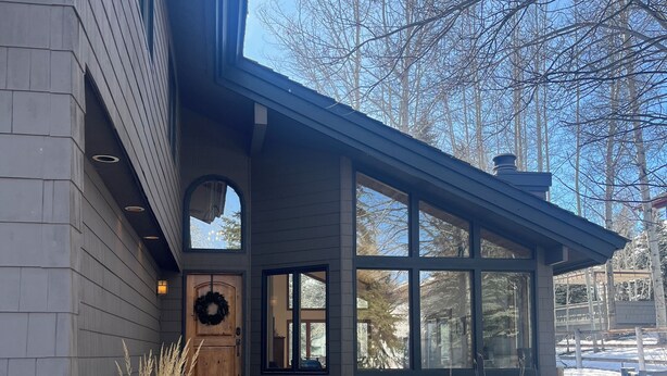 A modern house with a stone foundation, a wooden front door, and large windows. - 4-bedroom family home in charming Sun Valley close to Baldy and trails! (Sun Valley)