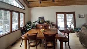 A dining room with a wooden table and chairs, large windows, and a ceiling with exposed beams. - 4-bedroom family home in charming Sun Valley close to Baldy and trails! (Sun Valley)