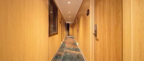 A hotel corridor with wooden walls and a carpeted floor.