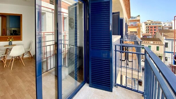 A balcony with a glass door and a view of the city.