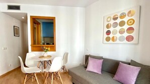 A modern living room with a grey sofa, white chairs, a small round table, and a blue cabinet.