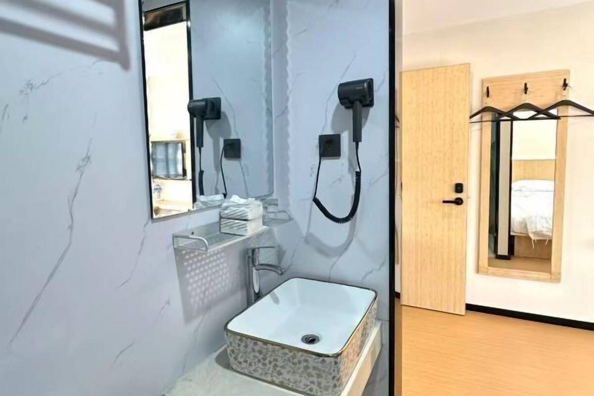 A bathroom with a white sink, a mirror, and two hair dryers mounted on the wall.