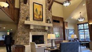 A spacious lobby with a stone fireplace, wooden beams, and modern lighting fixtures. - Ski-In/Out Luxury 1 Bedroom Condo / Sleeps 4 in Breckenridge at Peak 7 (Breckenridge)