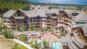 A resort with multiple buildings, a central pool area, and a mountainous backdrop. - Ski-In/Out Luxury 1 Bedroom Condo / Sleeps 4 in Breckenridge at Peak 7 (Breckenridge)