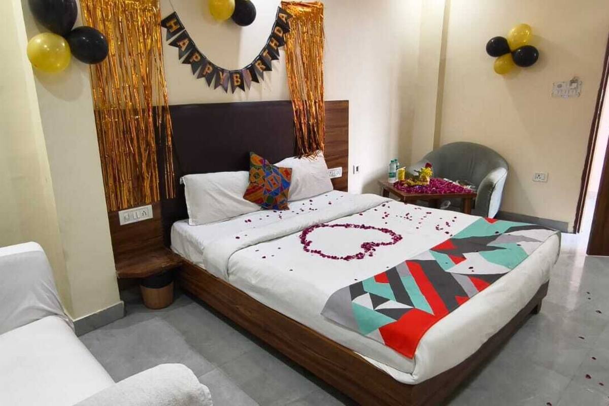A hotel room with a bed, a chair, a nightstand, and a wall-mounted clock.