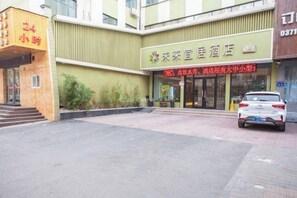 Ein Hotel mit grüner Fassade, ein Auto vor der Einfahrt und ein Schild mit chinesischen Schriftzeichen.