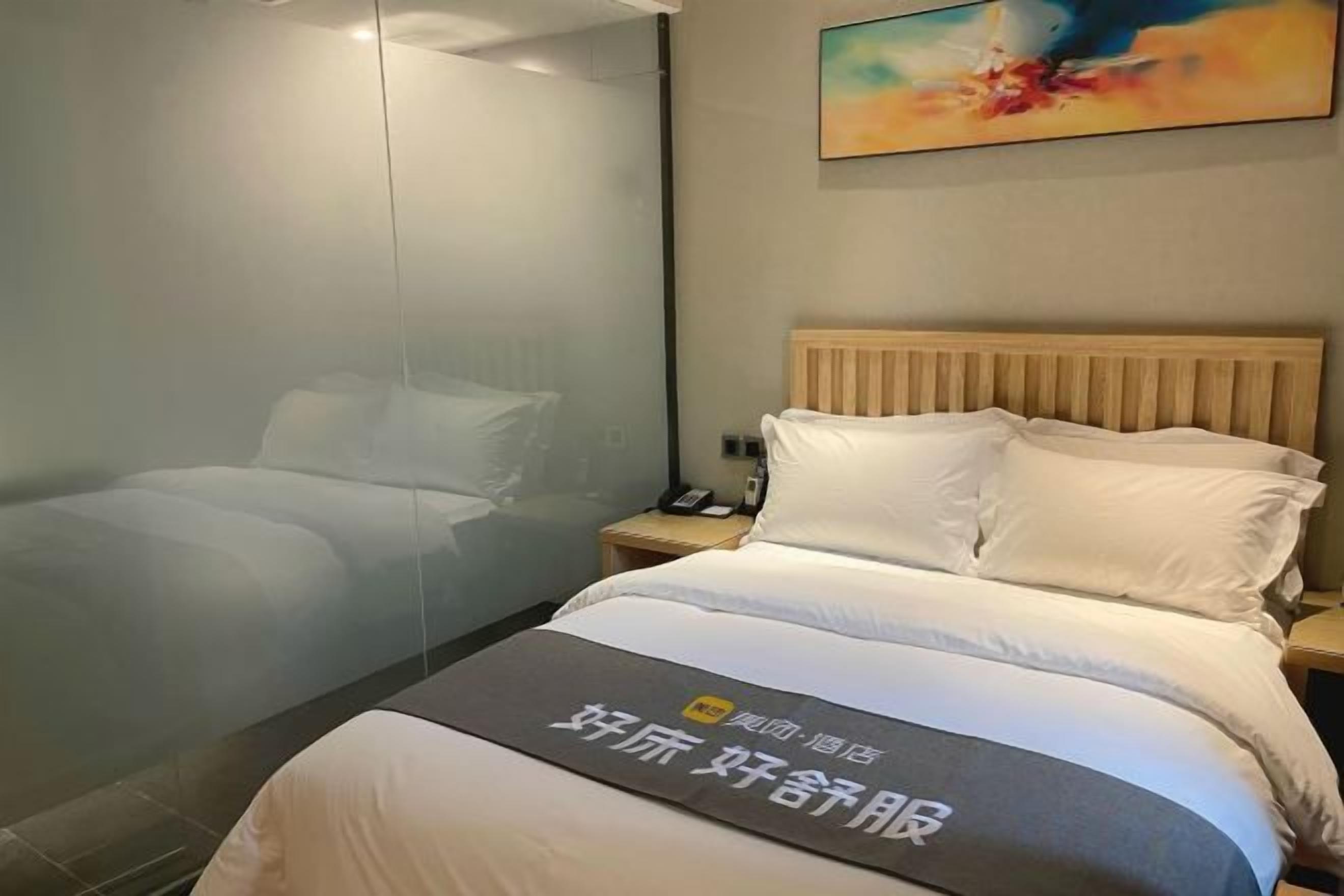 Una habitación de hotel con una cama, una mesita de noche y un cuadro en la pared.