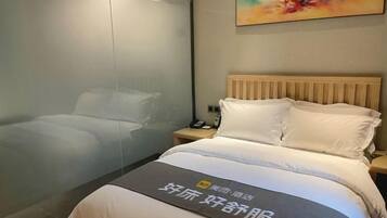 Una habitación de hotel con una cama, una mesita de noche y un cuadro en la pared.