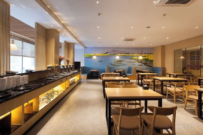 Un restaurante con barra de buffet, mesas y sillas.