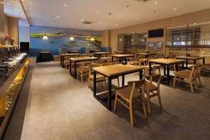 A restaurant with multiple tables and chairs, a counter with a display, and a mural on the wall.