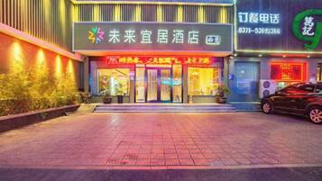 A hotel entrance with a signboard, a reception desk, and a car parked outside.