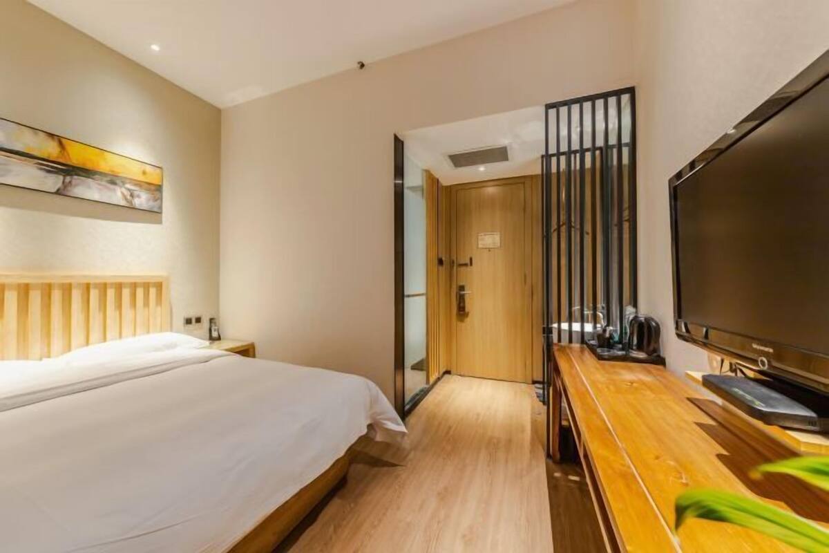 Une chambre d’hôtel avec un lit, un bureau en bois avec une télévision et une porte donnant sur une autre pièce.