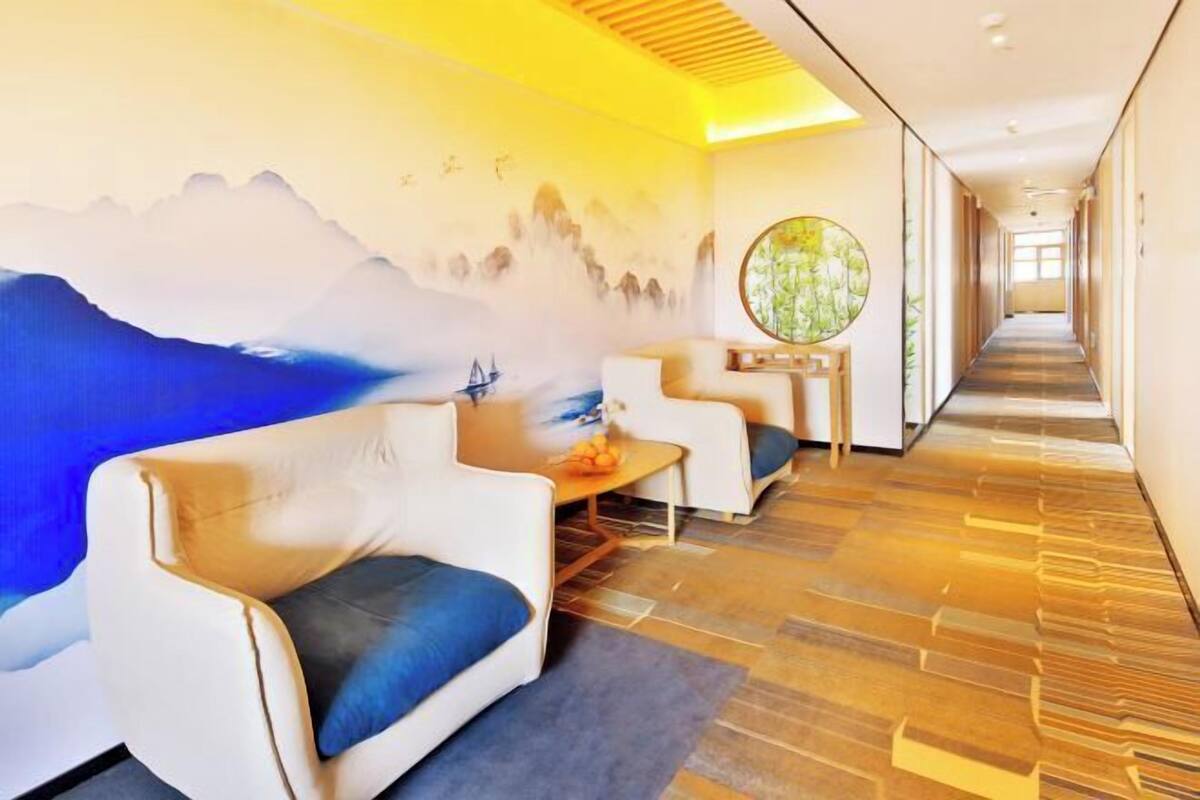 Un hall d’hôtel agrémenté d’une fresque murale, d’un espace salon et d’un long couloir.