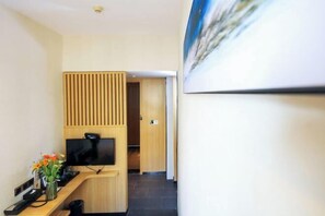 A reception desk with a flat-screen TV, a vase with flowers, and a wooden panel wall.