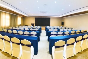 Ein Konferenzraum mit Tischen, Stühlen, einer Projektionsleinwand und einem Rednerpult.