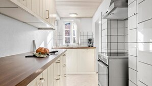 Une cuisine moderne avec des meubles blancs, un plan de travail en bois, un four en acier inoxydable et une fenêtre offrant une belle vue.