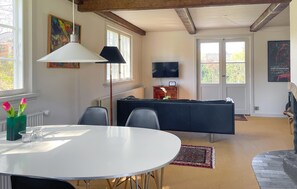 Un soggiorno moderno con un tavolo da pranzo rotondo, un divano, una televisione e un camino.