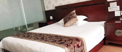 A hotel room with a bed, bedside table, and a nightstand.