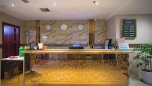 A reception desk with a marble wall, a digital display, and a potted plant. - FanYing Business Hotel (Huzhou)
