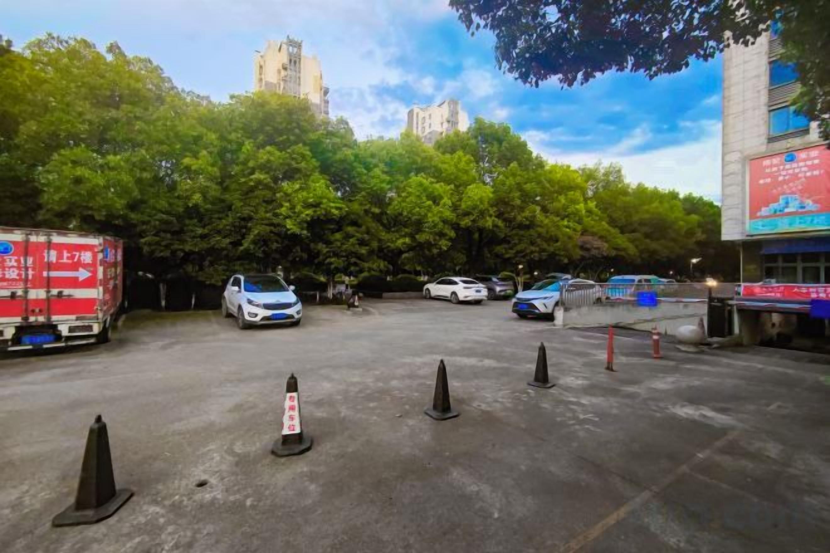 A parking lot with several cars, a red truck, and traffic cones.