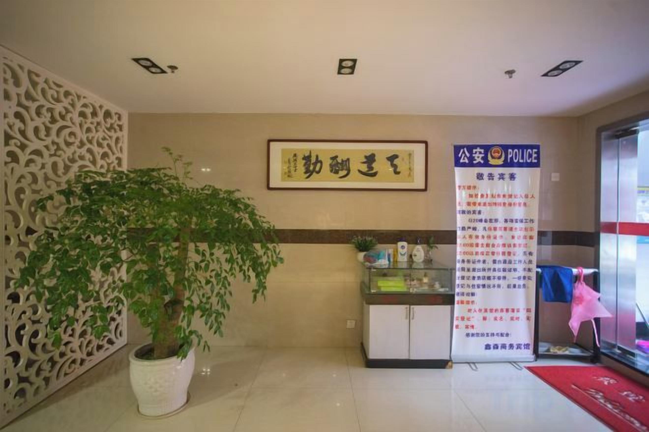 A reception area with a potted plant, a wall-mounted sign, and a glass display case with items.
