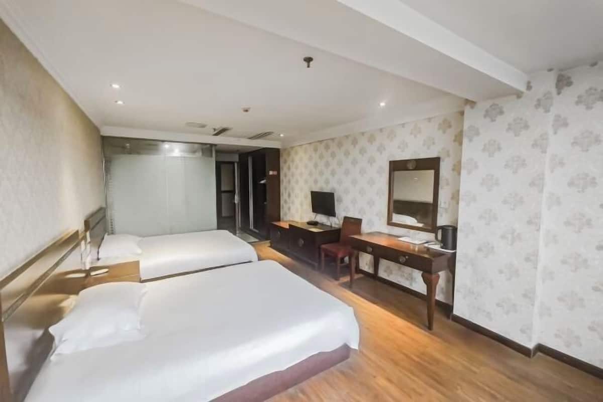 Une chambre d’hôtel avec deux lits, un bureau, une chaise, une télévision et un miroir.
