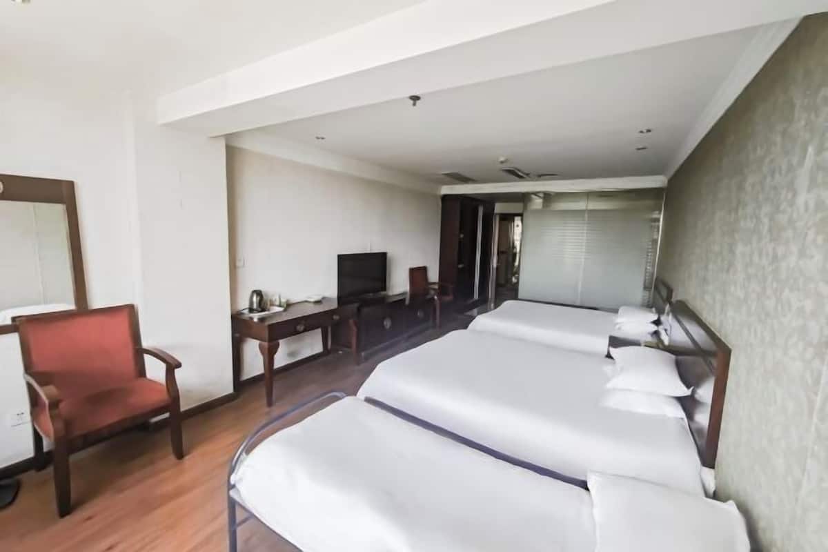 Une chambre d’hôtel avec deux lits, un bureau, une chaise et un téléviseur.