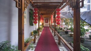 A corridor with a red carpet, wooden beams, and potted plants. - FanYing Business Hotel (Huzhou)