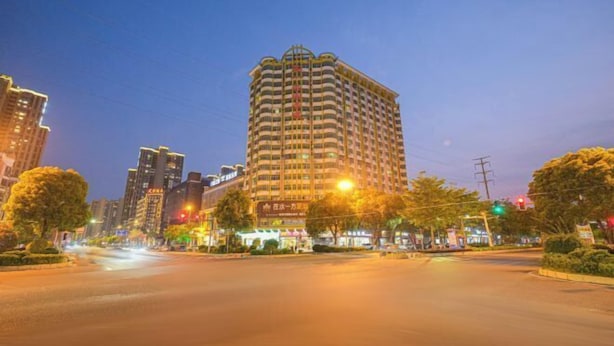 A multi-story hotel with a curved facade, located at a city intersection with visible traffic lights and street lamps. - Anxin Intercity Hotel (Quanzhou Quangang) (Quanzhou)