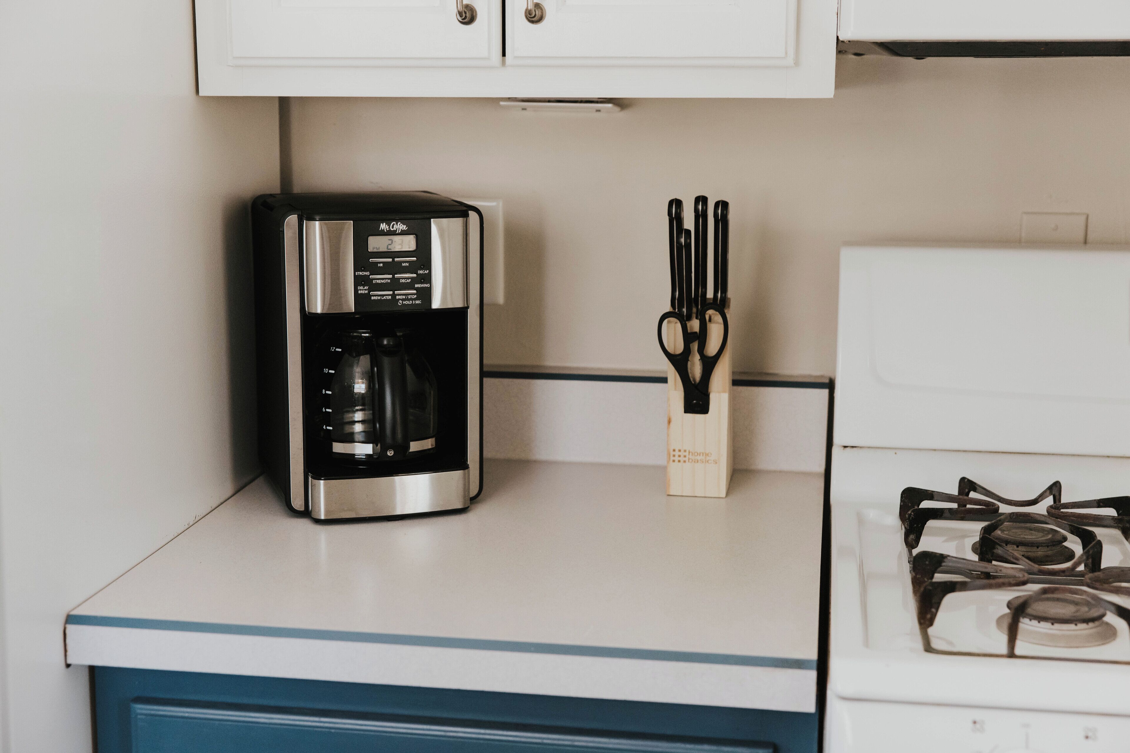 Una cocina con cafetera, juego de cuchillos y estufa.