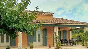 A two-story house with a tiled roof, green shutters, and a covered patio with outdoor furniture. - Luxurious home in Sarrians (Sarrians)