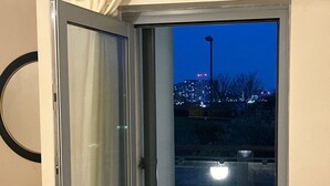 A room with a sliding glass door leading to an outdoor area with a cityscape view at night. - Flat in Greenwich Near O2 and London City Airport (London)