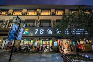 A building with a sign that reads '78' and '酒家' indicating a bar or restaurant. There are bicycles parked outside and a tree in the foreground. - Haojiang Hotel (Jishui)